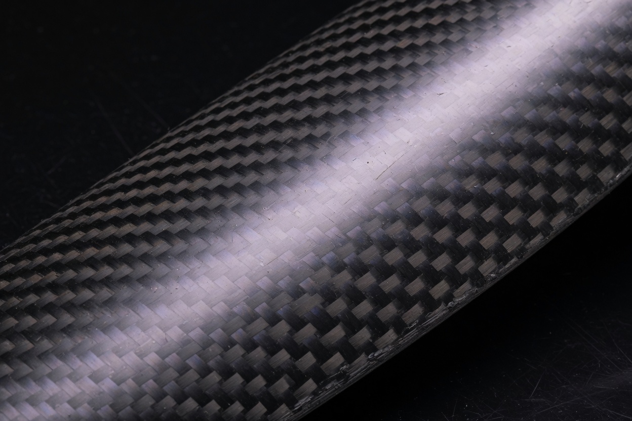 Extreme close-up of carbon fiber twill weave on a curved blade surface